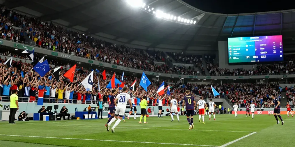 Fans cheering during a thrilling gà vàng tv football match with intense players and bright stadium lights.